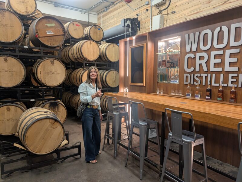A Venus sister posing in front of whiskey barrels at Woody Creek Distillery