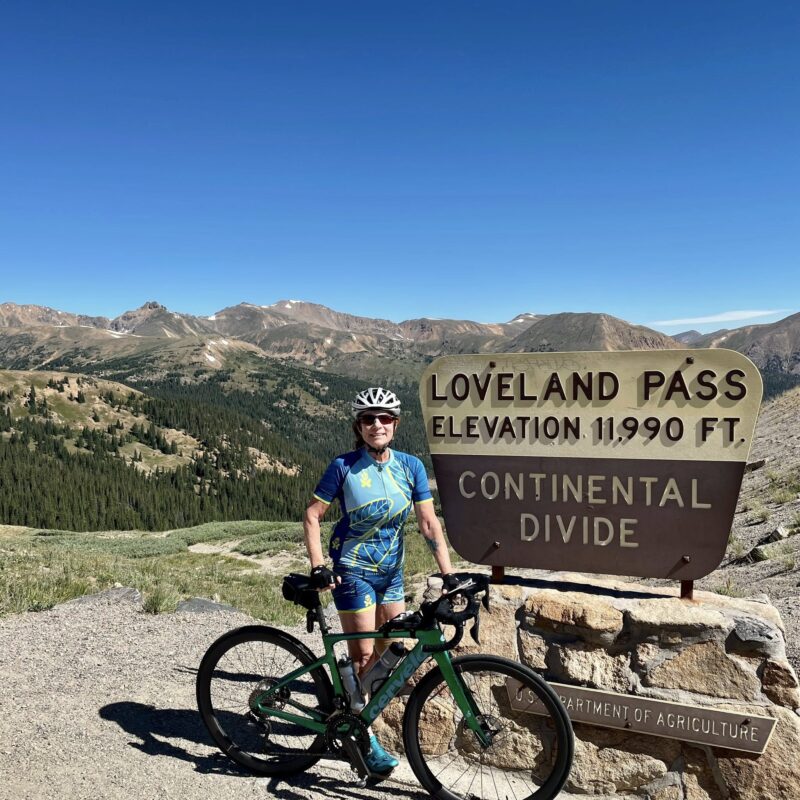 Venus member standing by the Loveland Pass sign at the Continental Divide