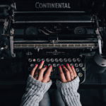 Old typewriter with woman's hands on the keys