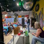 Female emcee on the stage pouring a glass of wine while the audience observes